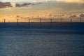 Wind farm in the open sea during sunset. Offshore wind generators. Renewable and green energy concept.