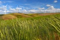 Wind farm turbines white on hill contrast green grass and blue sky, usa Royalty Free Stock Photo