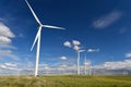 Wind farm turbines white on hill contrast green grass and blue sky, wa Royalty Free Stock Photo