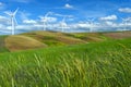 Wind farm turbines white on hill contrast green grass and blue sky, wa Royalty Free Stock Photo