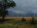 Wind generators are built on a wheat field against the background of a stormy sky Royalty Free Stock Photo