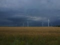 Wind generators are built on a wheat field against the background of a stormy sky Royalty Free Stock Photo