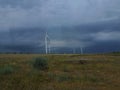 Wind generators are built on a wheat field against the background of a stormy sky Royalty Free Stock Photo