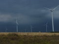 Wind generators are built on a wheat field against the background of a stormy sky Royalty Free Stock Photo