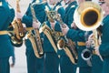 A wind instrument parade - people in green costumes holding saxophone