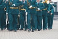 A wind instrument parade - people in green costumes walking on the street holding instruments