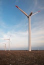 Wind power generators at a windmill farm in a plowed field and a blue sky background. Royalty Free Stock Photo