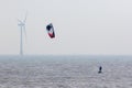 Wind power. Kitesurfer surfing by offshore windfarm turbine. Green energy