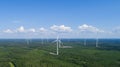 Wind power plant in the green field view and distant forest at summer evening. Concept of clean energy.