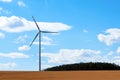 Wind power station with one pole and windmill, near forest and cornfield in countryside under blue sky with clouds Royalty Free Stock Photo