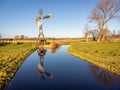 Wind power station Windmill on a river in the middle of fields and meadows with a blue sky Royalty Free Stock Photo