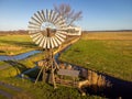 Wind power station Windmill on a river in the middle of fields and meadows with a blue sky Royalty Free Stock Photo