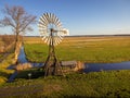 Wind power station Windmill on a river in the middle of fields and meadows with a blue sky Royalty Free Stock Photo