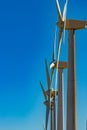 Wind power stations. Telephoto lens shot. A row of turbines near the seashore. Wind farm eco field. Eolic park with blue sky in Royalty Free Stock Photo