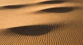 Wind-sculpted desert sand dunes exhibit a pattern of fine, parallel ripples creating a textured Royalty Free Stock Photo