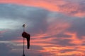 Wind sock under at the dawn under the red orange glowing sky with cirrus and cumulus clouds