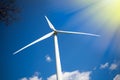 Wind and solar power. Turbine in sunshine against blue sky.