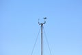 Wind speed and direction instruments mounted on top of tall metal pole held together with three strong wires