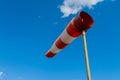 Wind speed meter, red and white stripes on blue background. Windsock indicator of wind on runway airport Royalty Free Stock Photo