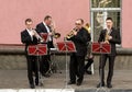 Wind street ensemble saxophone trumpet, a city day celebration. Four musicians in classic black suits play on wind instruments Royalty Free Stock Photo