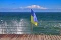 The wind-torn Ukrainian flag against the backdrop of a turbulent sea Royalty Free Stock Photo