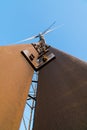 Wind turbine against a clear blue sky. Rusty metal structure with struts and rivets at an old wind turbine farm on a sunny day. Royalty Free Stock Photo