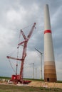 Wind turbine construction site at wind park with crane and completed wind turbines in the background during cloudy day Royalty Free Stock Photo