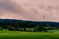 Wind turbine, cow, meadow and trees. Cattle grazing on the meadow with wind turbine and trees in the background. Royalty Free Stock Photo