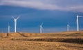 Wind turbine farm in a yellow field, meadow, on a bright blue sky background with clouds Royalty Free Stock Photo