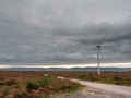 Wind turbine in a field. Grey cloudy sky in the background. Nobody. Renewable energy source Royalty Free Stock Photo