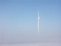 Wind turbine in misty snowy landscape against blue sky Royalty Free Stock Photo