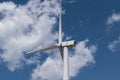 Wind turbine nacelle with propeller for electric energy production against cloudy sky in summer, ecological alternative and Royalty Free Stock Photo