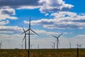Wind turbine on Oklahoma prarie behind barbed wire fence - selective focus - under blue cloudy sky Royalty Free Stock Photo