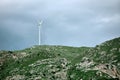 Wind turbine over a rocky mountaintop covered with green plants Royalty Free Stock Photo