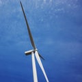 Wind turbine producing alternative energy on the background of blue sky. Royalty Free Stock Photo
