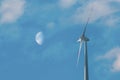 Wind turbine producing clean and renewable energy on blue sky with Moon background Royalty Free Stock Photo