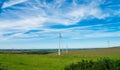 Wind turbine - renewable energy source on green meadows with sea on horizon. The concept of environmental protection and Royalty Free Stock Photo