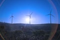 A wind turbine is silhouetted by the setting sun