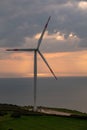 Wind turbine at sunset, on a hill with sea view. Royalty Free Stock Photo