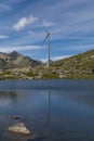 Wind turbine at the top of the Gotthard pass in the Swiss Alps is reflected in the water of the lake