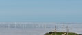 Wind turbines above a foggy valley with aerials and antennas on a hilltop in the foreground