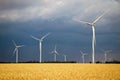 Wind turbines and agricultural field on a summer cloudy day. Energy production, clean and renewable energy