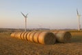 Wind turbines and bales of hay in a field Royalty Free Stock Photo