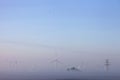 Wind turbines in early morning mist on countryside of ostfriesland in lower saxony Royalty Free Stock Photo