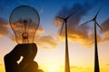 Wind turbines and electrical light bulb in hand. Royalty Free Stock Photo