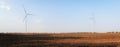 Wind turbines on field. Empty field in foreground, blue sky on background.