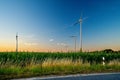 Wind turbines in green grass field against sky during sunset Royalty Free Stock Photo