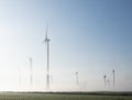 Wind turbines in green meadow near aurich in ostfriesland on misty morning in august