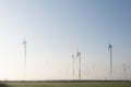 Wind turbines in green meadow near aurich in ostfriesland on misty morning in august