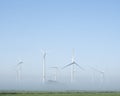 Wind turbines in green meadow near aurich in ostfriesland on misty morning in august